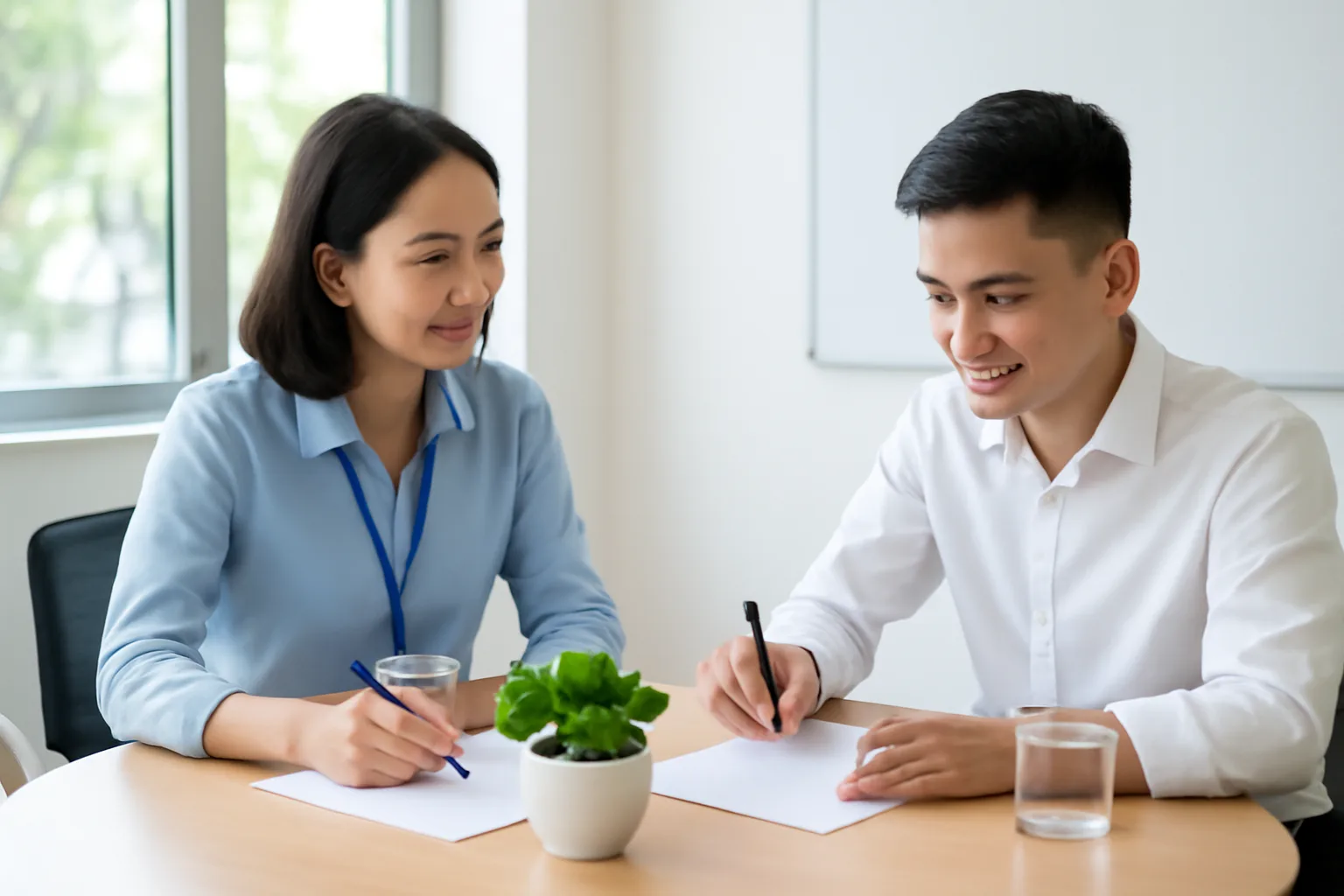 Nhân viên nhân sự và người lao động mới cùng ký hợp đồng lao động tại bàn họp